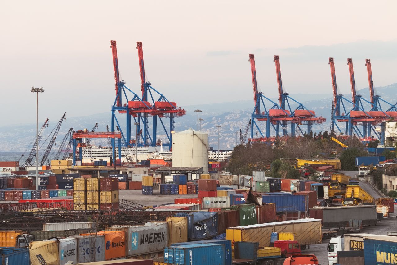 A bustling industrial view of Beirut port with cargo containers and towering cranes.
